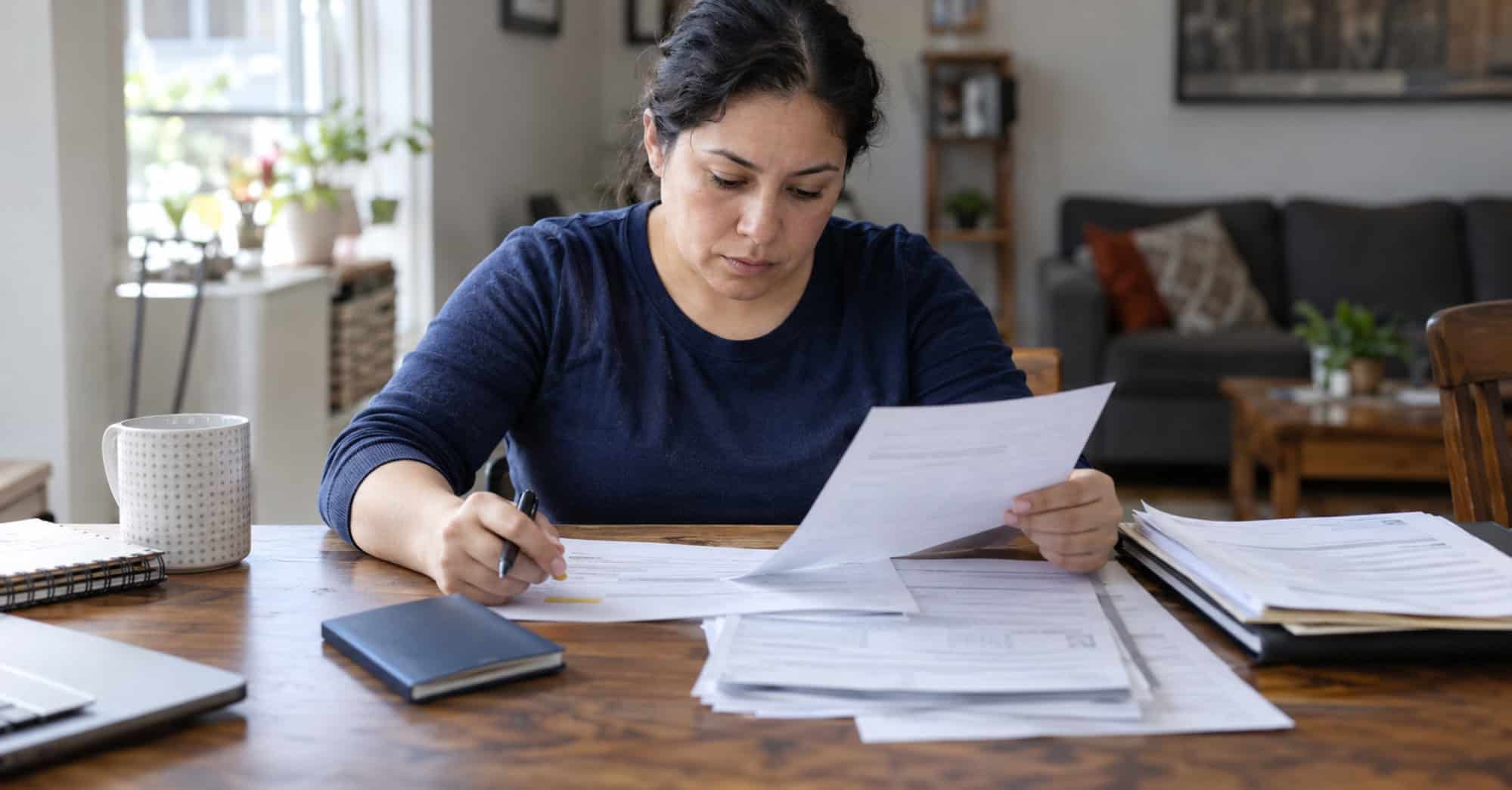 Persona adulta inmigrante revisando formularios y documentos relacionados con una solicitud de residencia permanente en Estados Unidos.